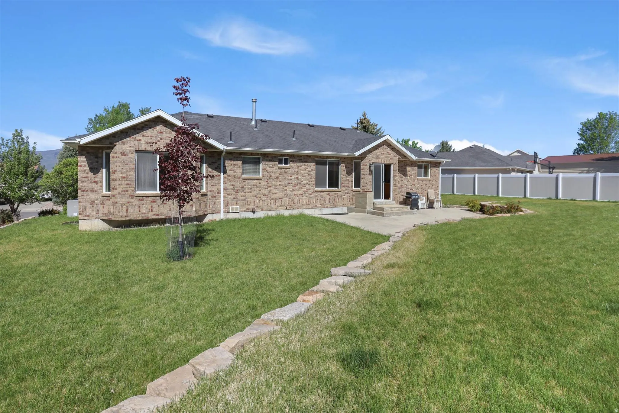Expansive backyard featuring a lush lawn and a stone retaining wall