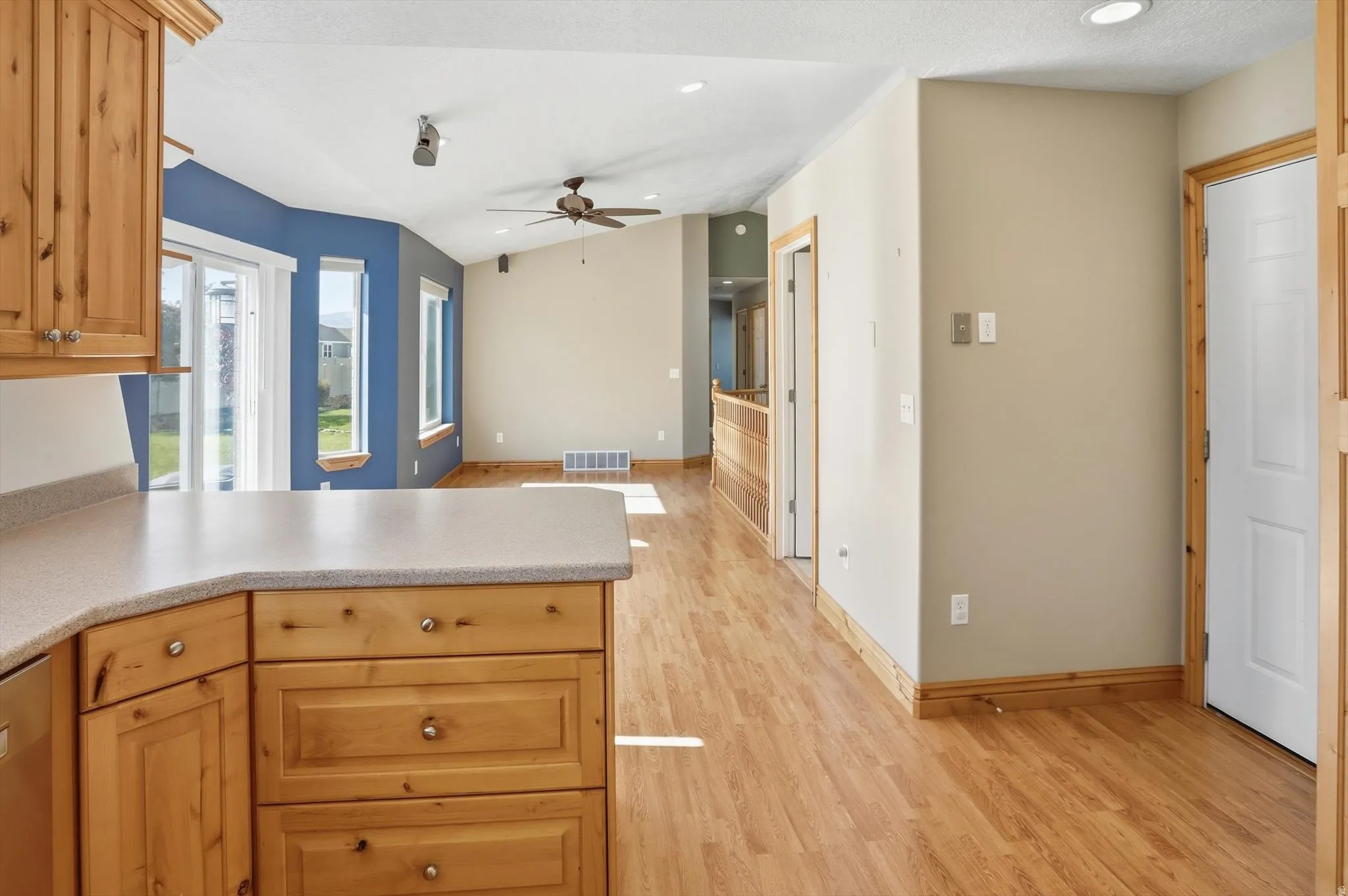 Kitchen and living area featuring wood-finish flooring, light wood cabinetry, and light-toned countertops