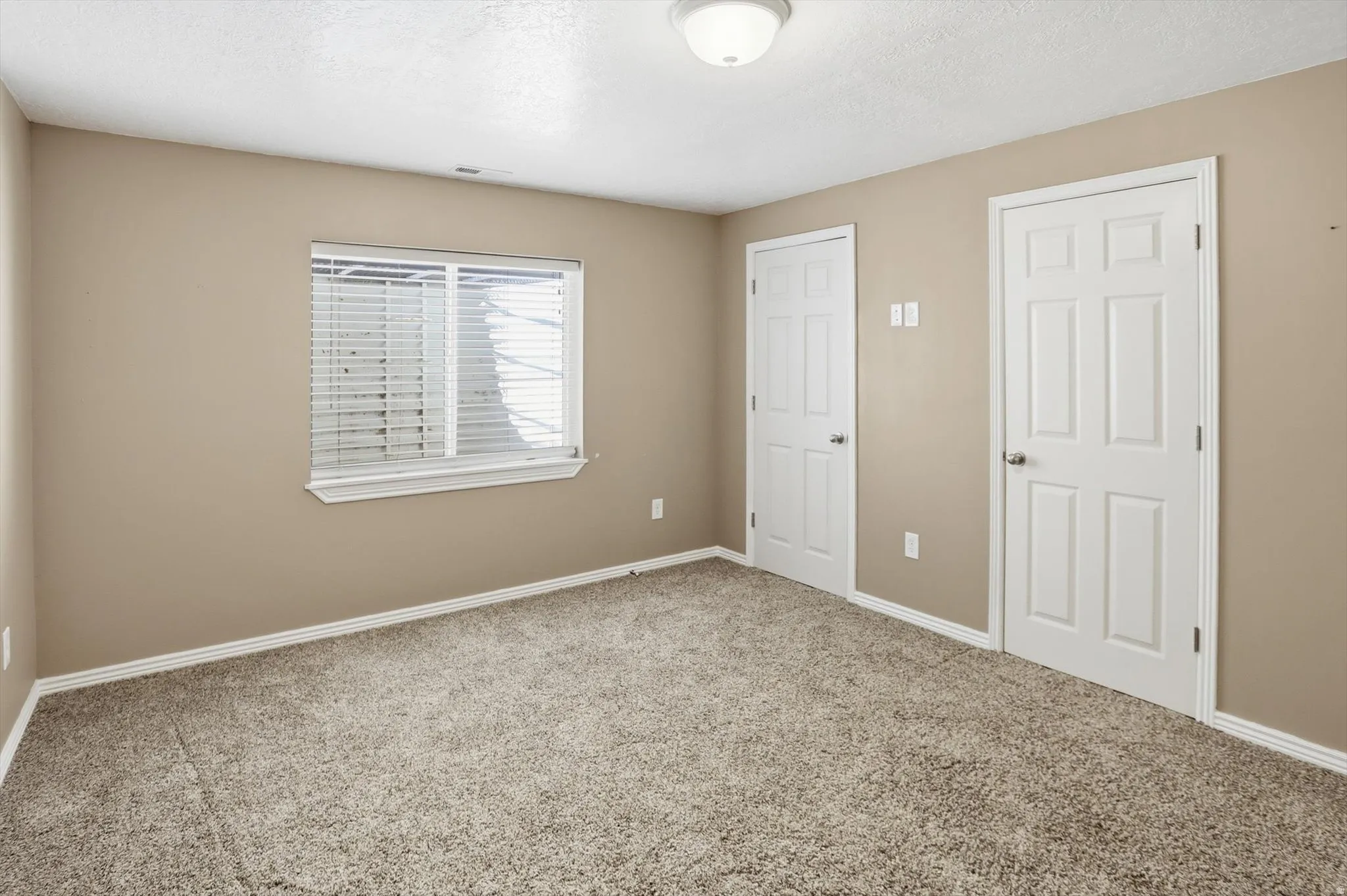 Carpeted interior space with neutral wall tones and white baseboards