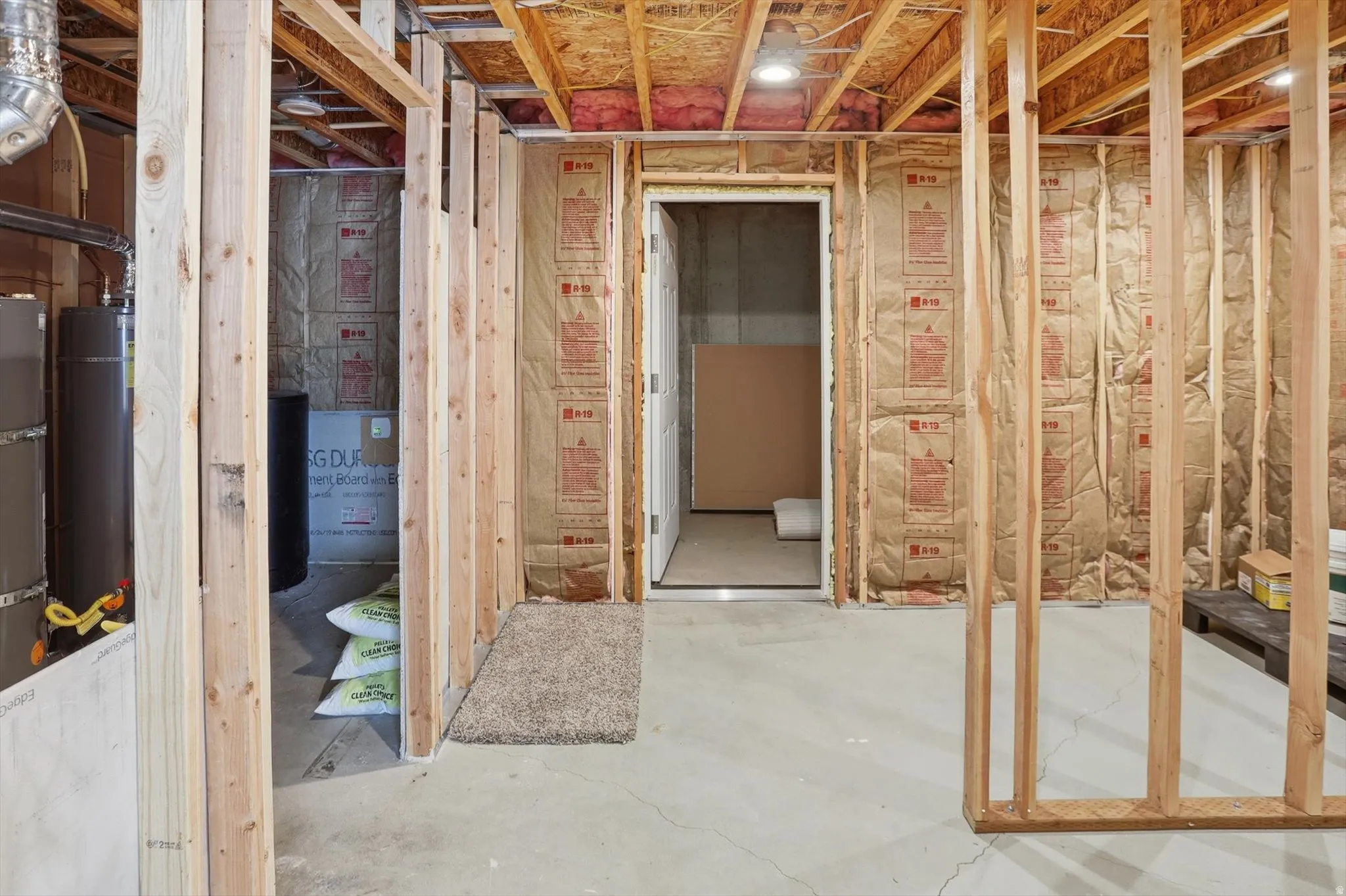 Unfinished basement space featuring exposed wooden framing, concrete flooring, and insulated walls