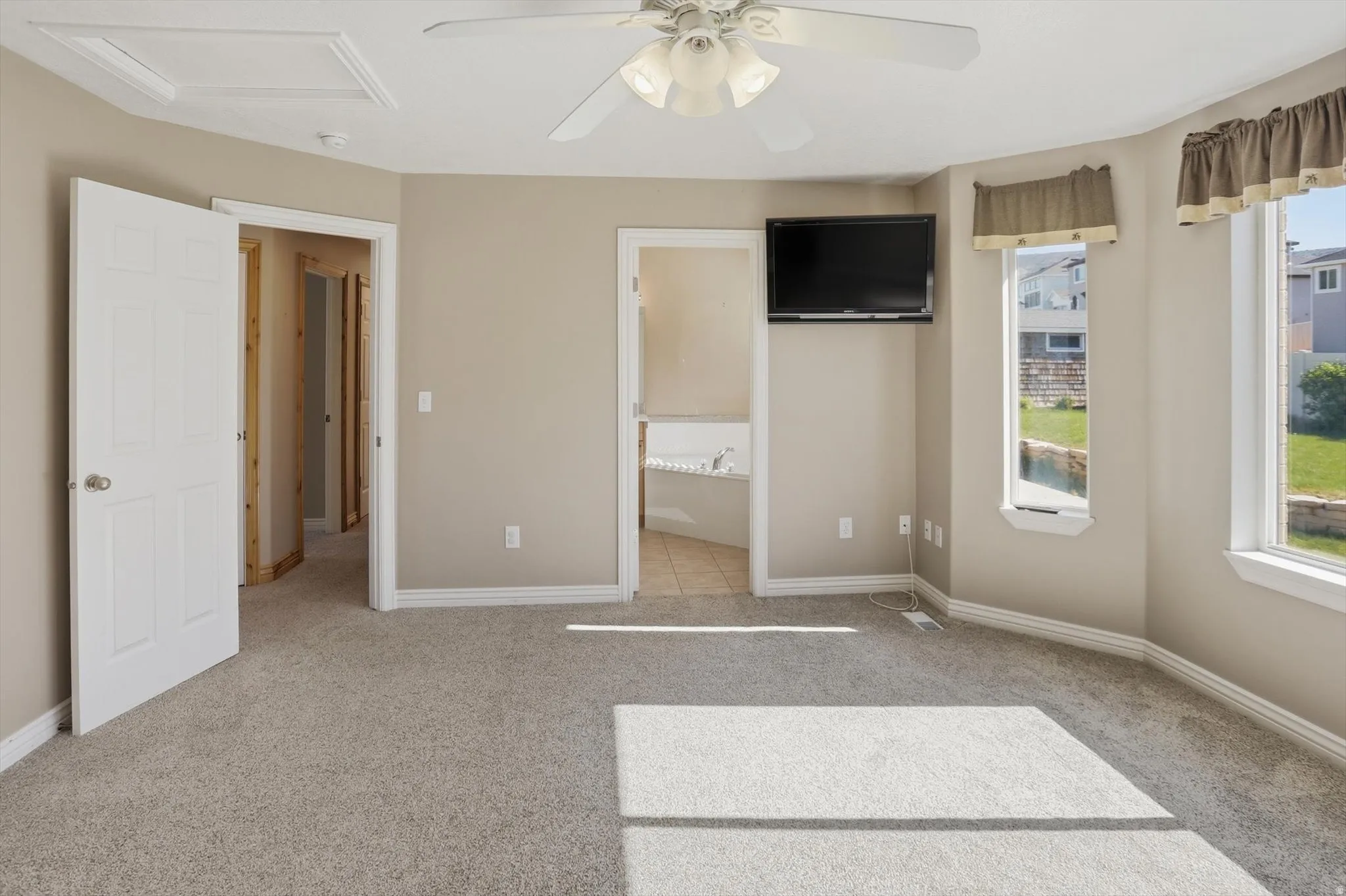 Carpeted interior space with light neutral wall tones, white trim, and a ceiling fan