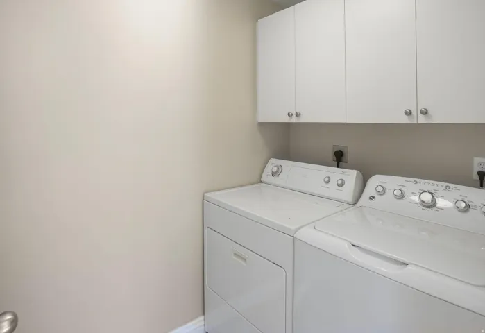 Dedicated laundry area featuring upper white cabinetry with brushed nickel hardware
