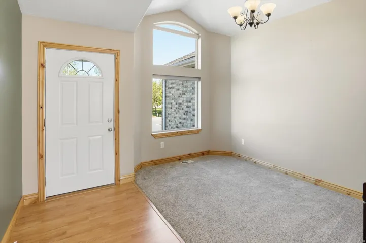 Entryway featuring a white paneled door with an arched glass insert, wood-finish flooring, and a decorative chandelier