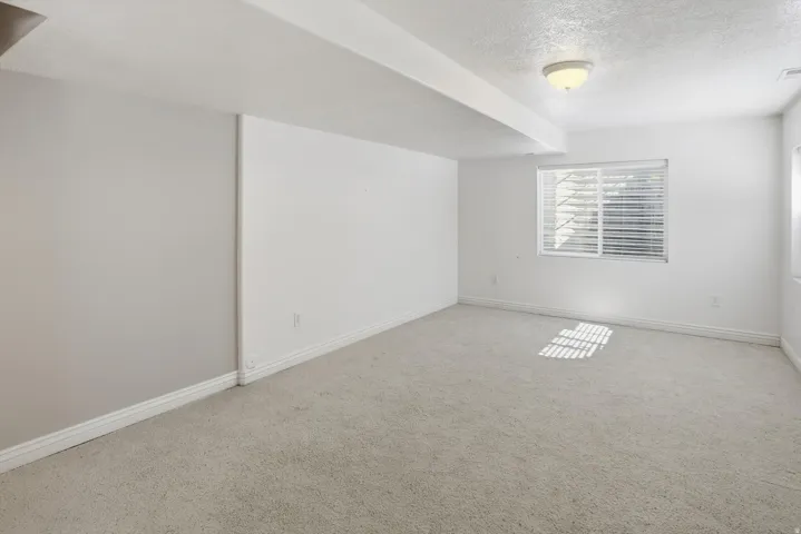 Spacious room featuring light-toned carpeting, white baseboards, and neutral wall paint