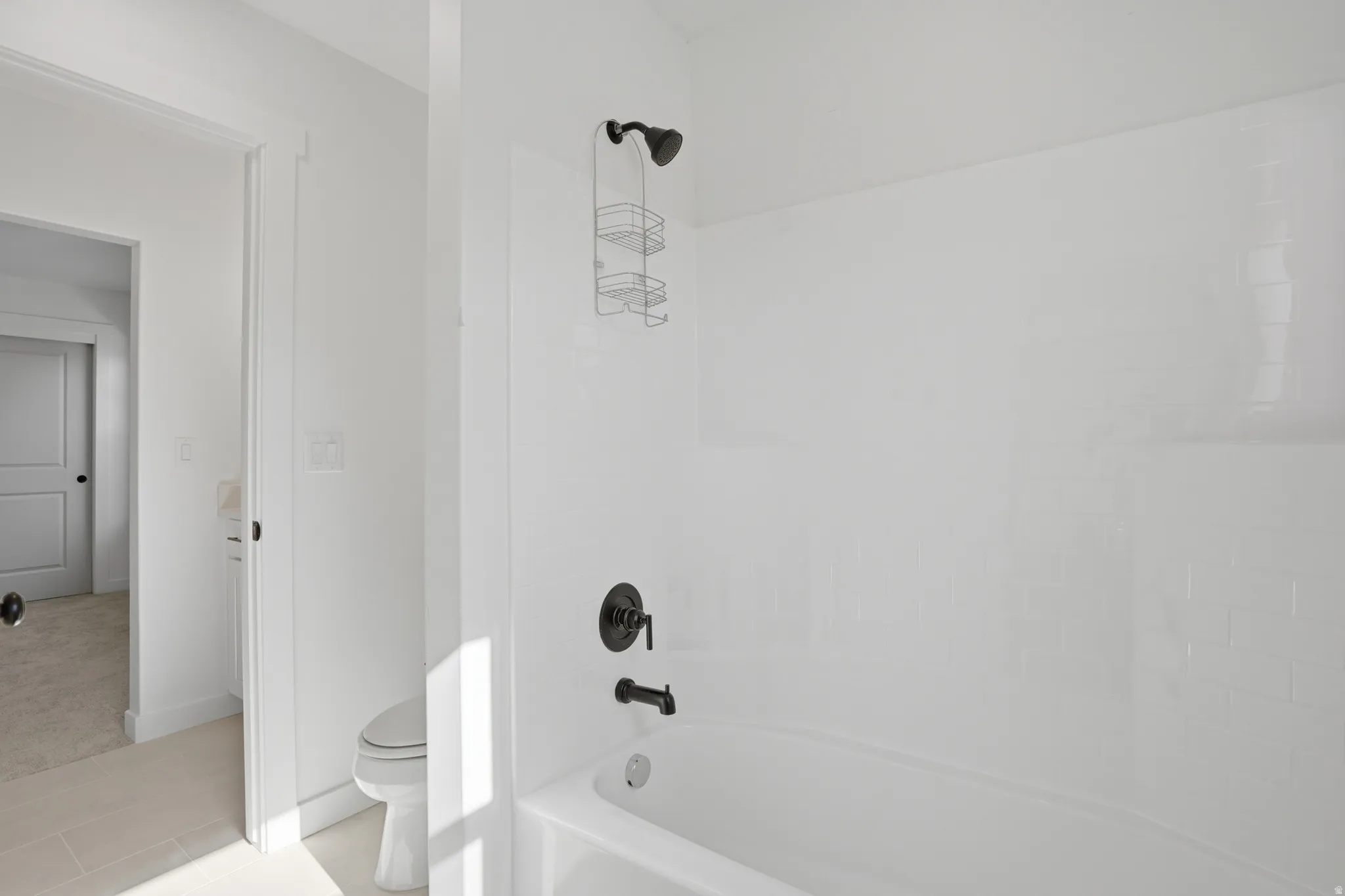 Bright white tub and shower combination featuring subway tile surround and matte black fixtures
