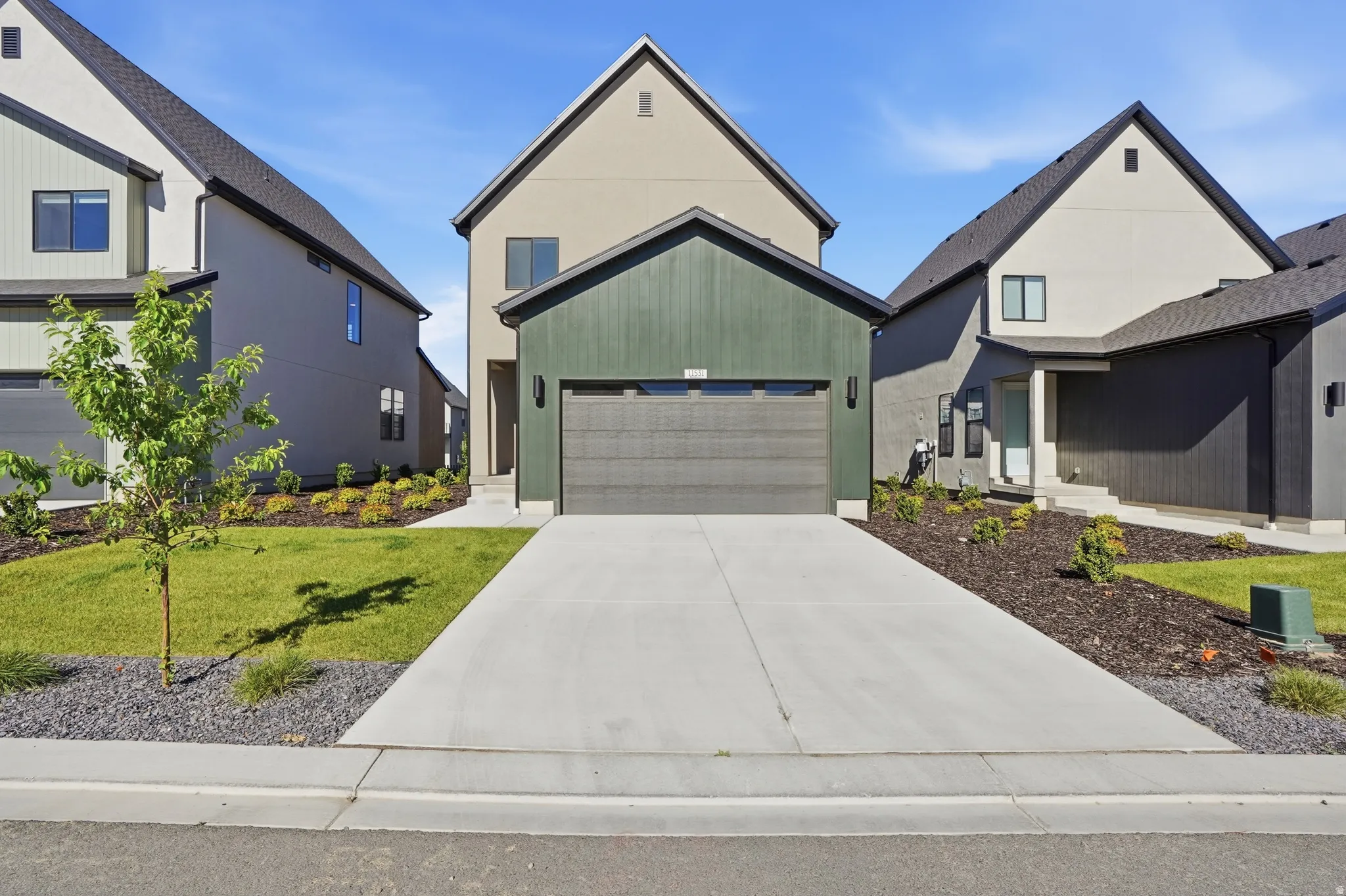 Contemporary exterior with a dark green facade and a contrasting light-colored stucco finish