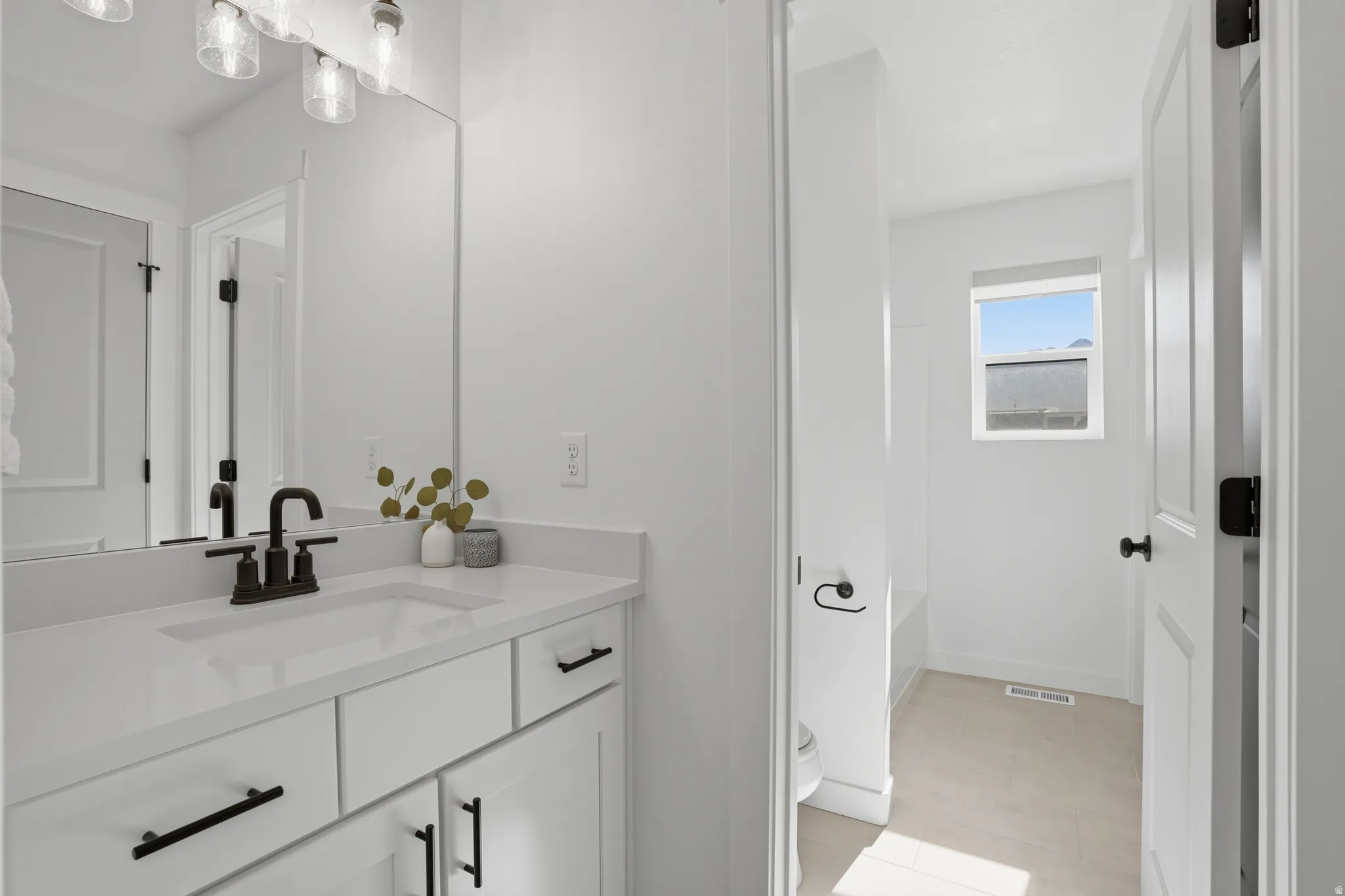 Bathroom featuring a single vanity with white cabinetry, a solid surface countertop, and a dark bronze faucet