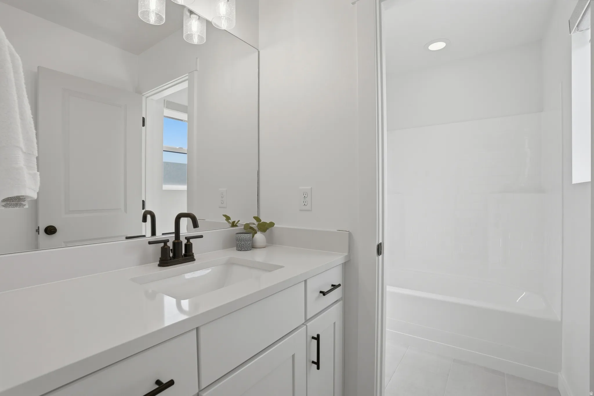 Bathroom featuring a single vanity with an integrated sink, white countertop, and dark-finished faucet