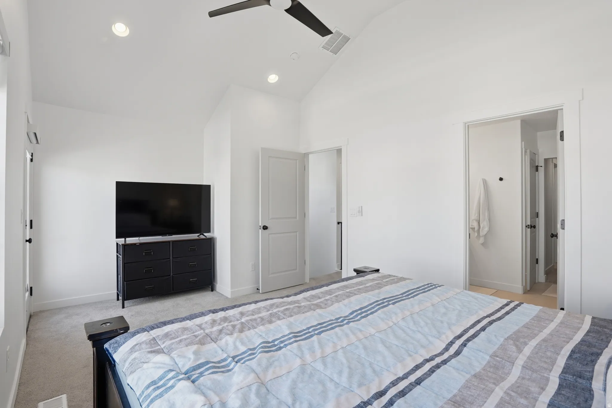 Vaulted ceiling room featuring recessed lighting, a modern ceiling fan, two doorways, and neutral carpeting