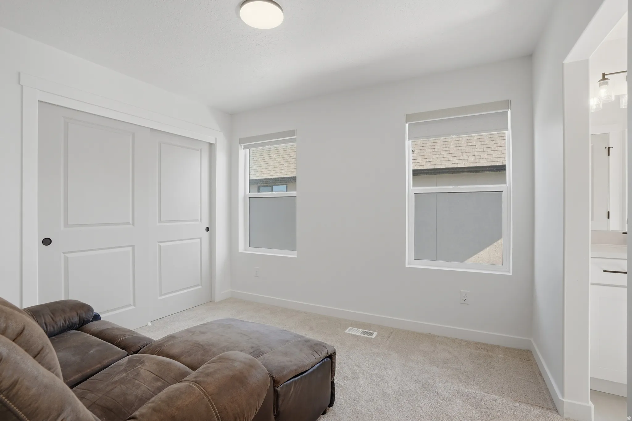 Bright interior space featuring light-colored carpeting, white walls, and a ceiling-mounted light fixture