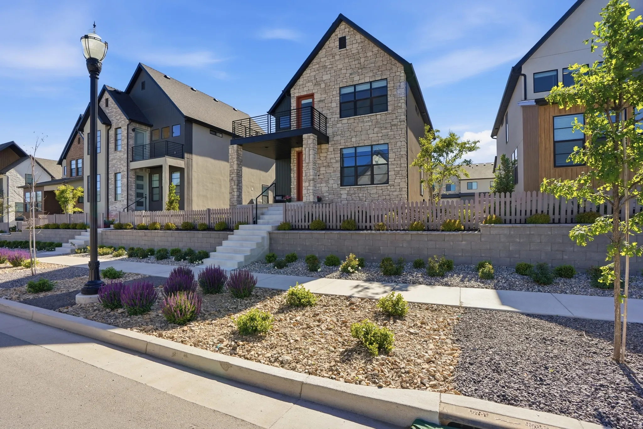 Contemporary stone and stucco exterior featuring a second-story balcony with black railings