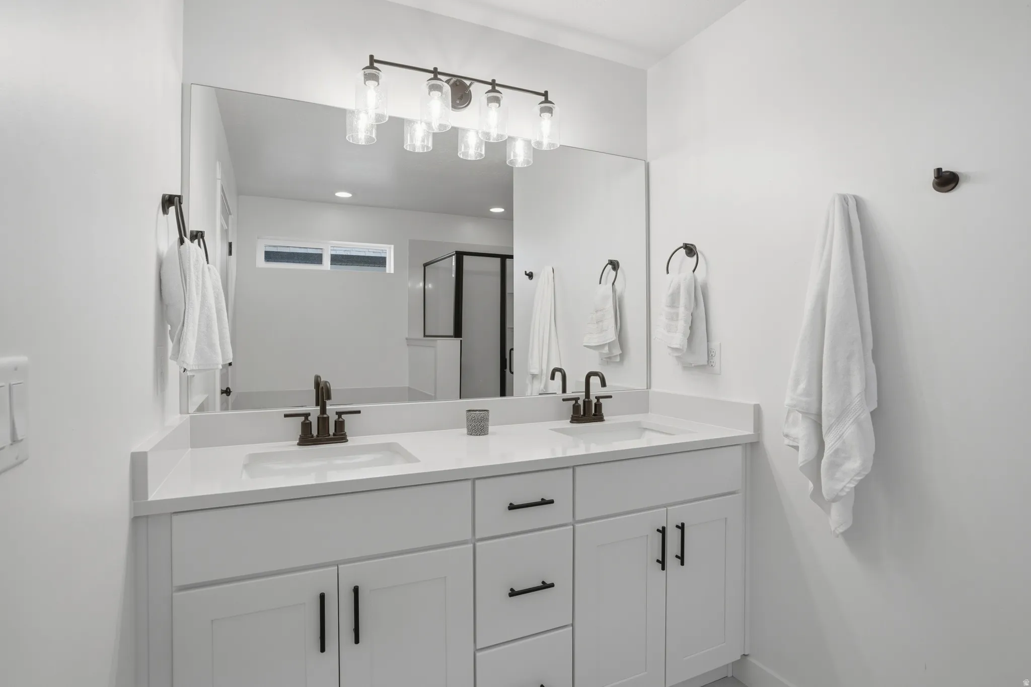 Dual vanity with white cabinetry and integrated sinks, complemented by dark bronze fixtures and hardware