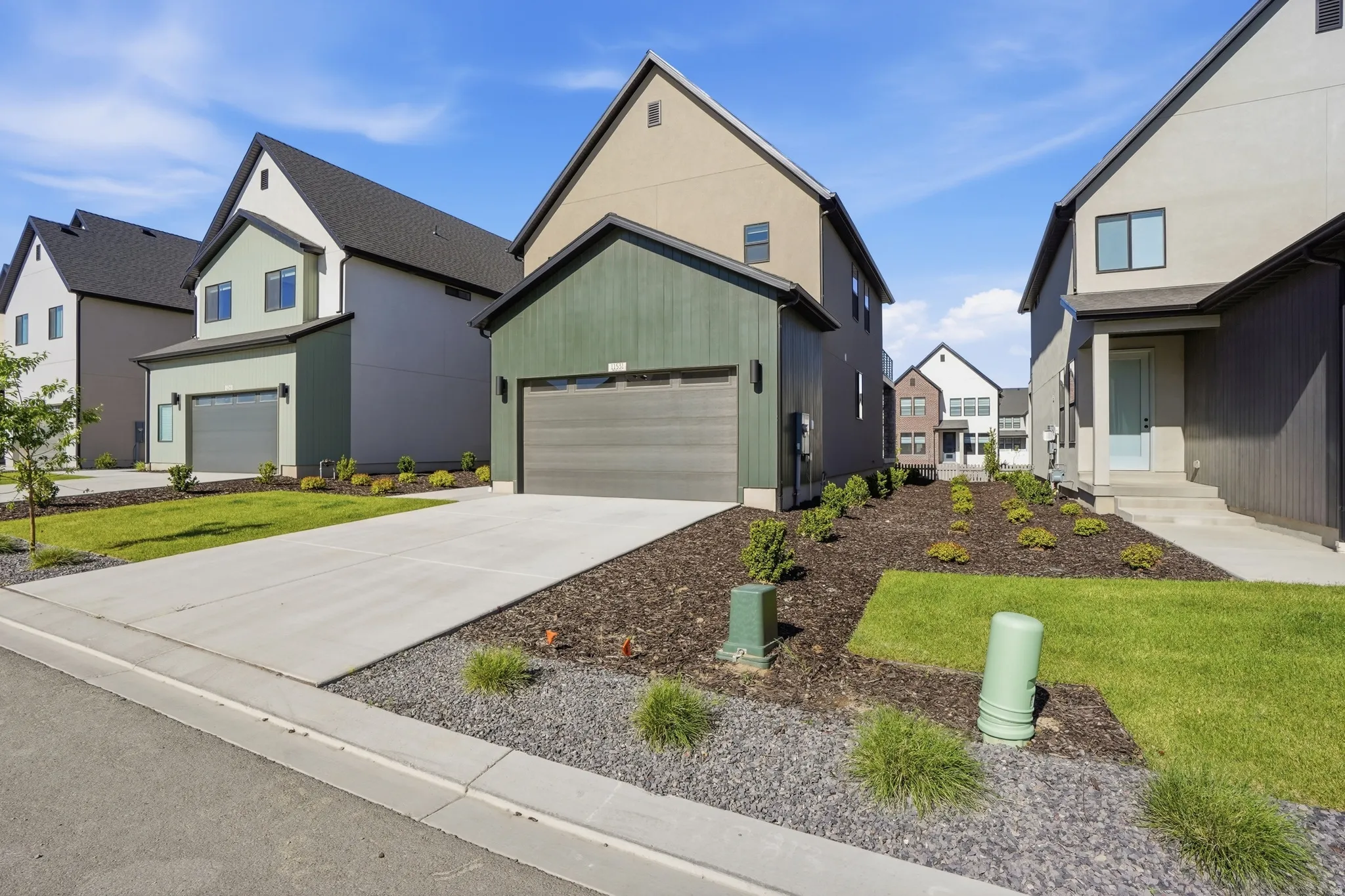 Contemporary exterior featuring a dark green vertical board and batten facade and an integrated garage with a modern sectional door