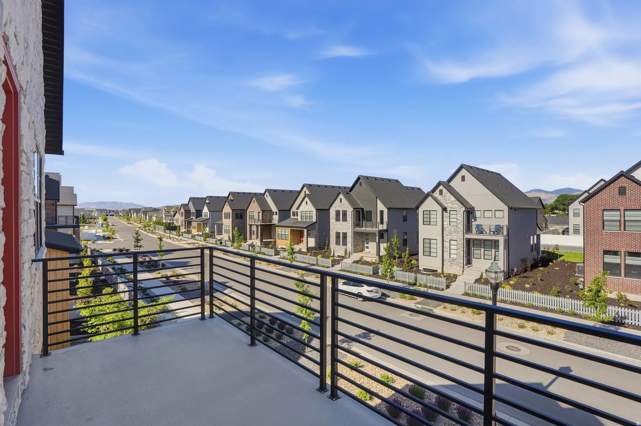 Balcony with horizontal railing overlooking a street lined with contemporary homes