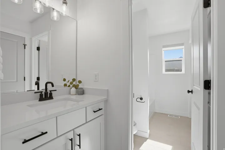 Bathroom featuring a single vanity with white cabinetry, a solid surface countertop, and a dark bronze faucet