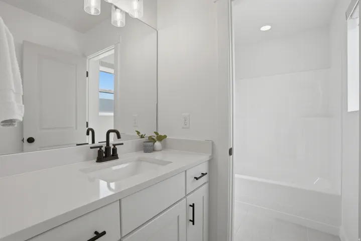 Bathroom featuring a single vanity with an integrated sink, white countertop, and dark-finished faucet