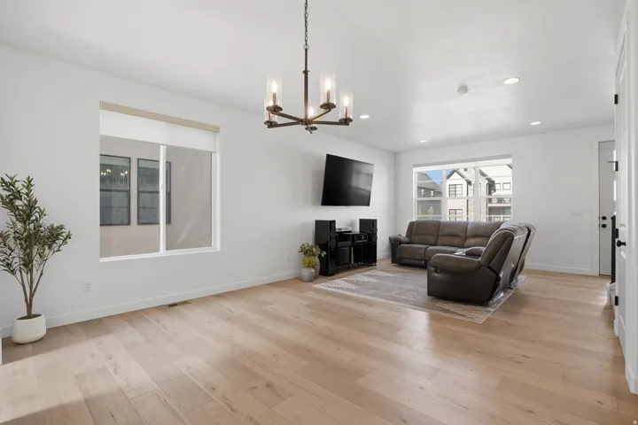 Bright living area featuring light wood-finish flooring, recessed lighting, and a modern bronze chandelier
