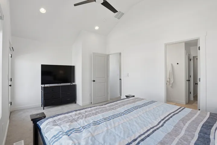 Vaulted ceiling room featuring recessed lighting, a modern ceiling fan, two doorways, and neutral carpeting
