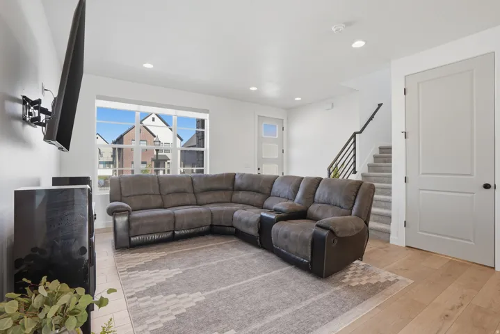 Living space featuring wood-finish flooring, recessed lighting, and a modern staircase with open balusters