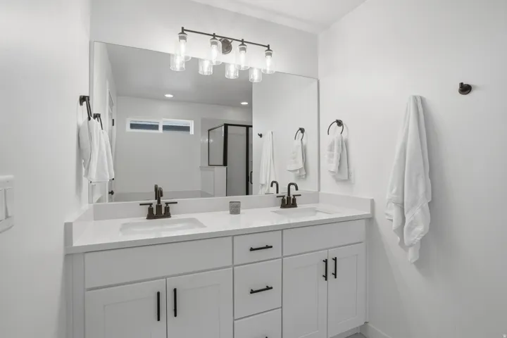 Dual vanity with white cabinetry and integrated sinks, complemented by dark bronze fixtures and hardware