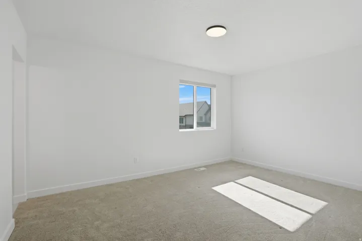Carpeted room featuring a single window with white trim, a flush-mount ceiling light, and white baseboards