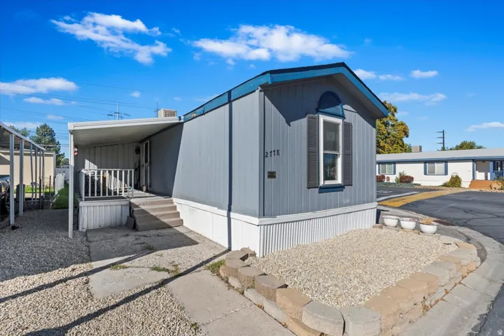 Gray mobile home with white trim and a covered entry porch