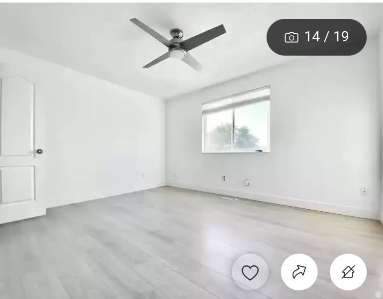 Bright room featuring light wood-finish flooring, white walls, and a modern ceiling fan with integrated lighting