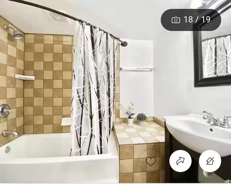 Bathroom featuring a white bathtub, ceramic tile surround, and a wall-mounted sink with a dark wood-finish vanity