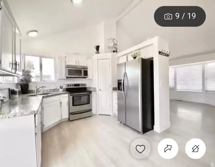 Kitchen featuring white cabinetry, stainless steel appliances, speckled countertops, and light wood-finish flooring