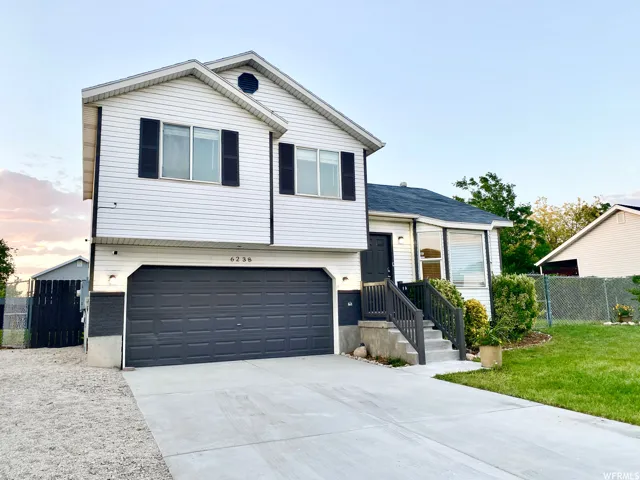 Split-level residence featuring white siding and black shutters