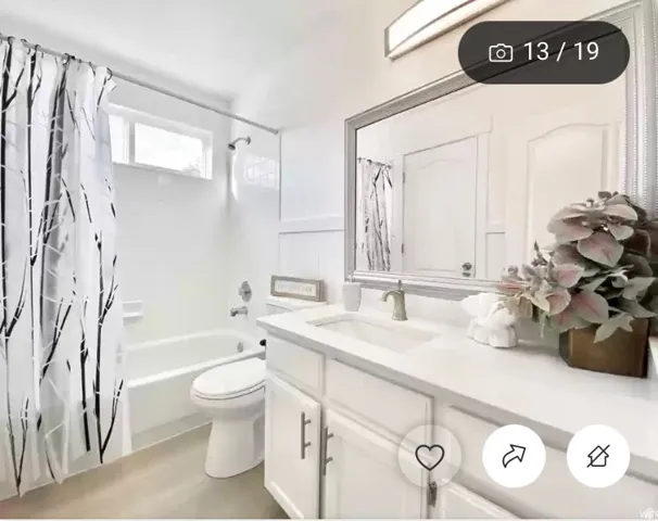 Bright bathroom featuring a white vanity with an integrated sink, a large framed mirror, and a white bathtub with tile surround