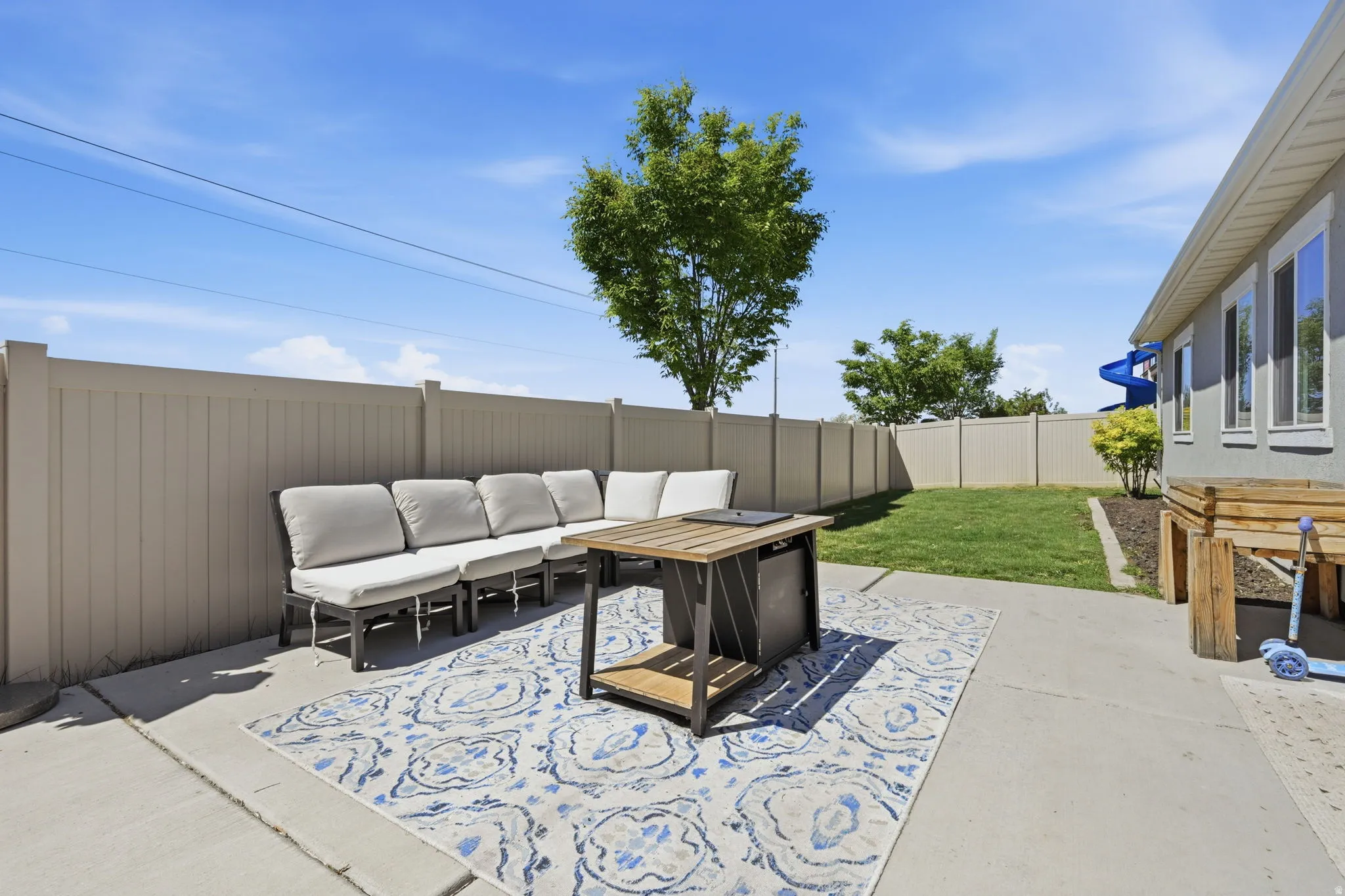 Spacious patio area with concrete surfacing, a surrounding privacy fence, and a manicured lawn