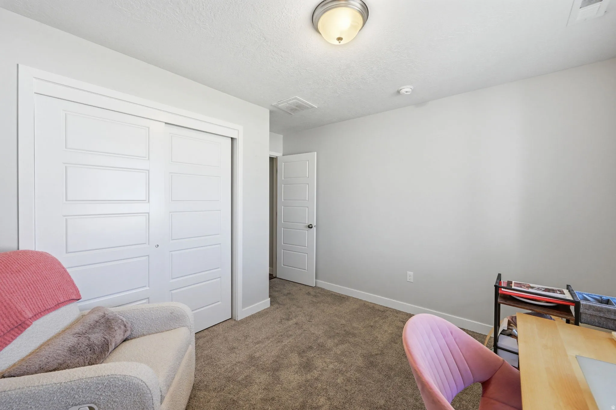 Neutral-toned room featuring a large closet with panel doors, recessed baseboards, and carpeted flooring