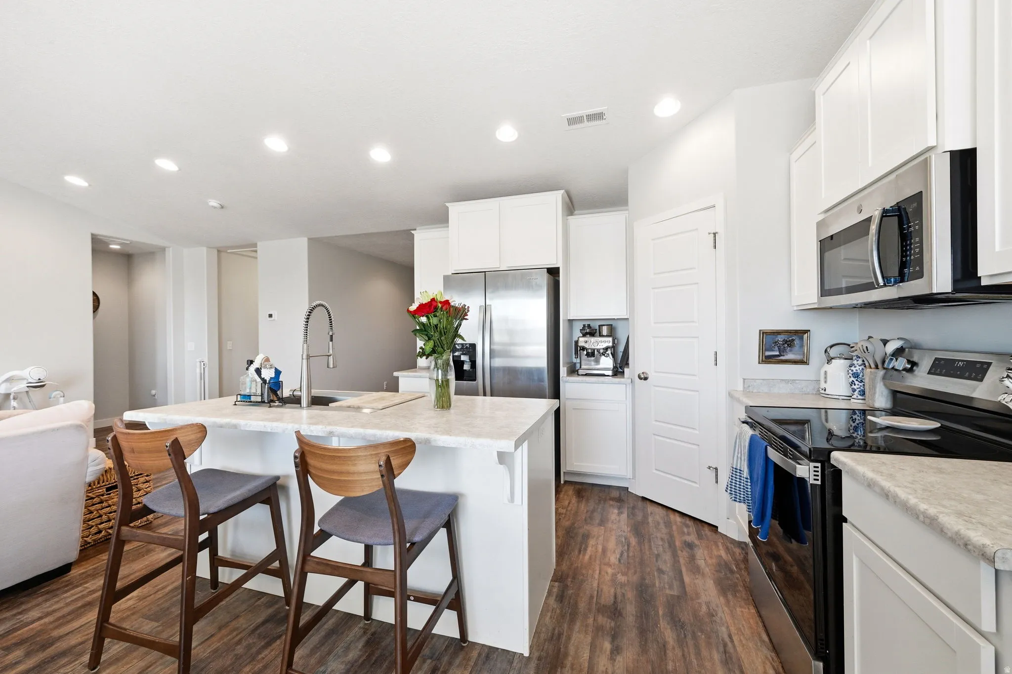 Kitchen featuring wood-finish flooring, white cabinetry, stainless steel appliances, and light-toned countertops