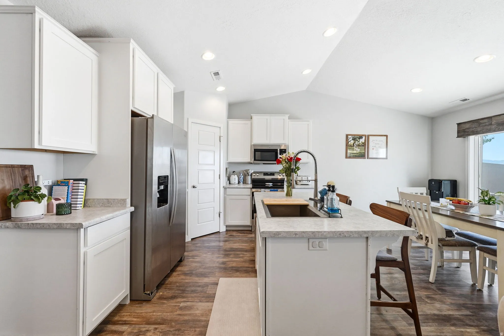 Modern kitchen featuring a central island with an undermount sink, light-toned countertops, and wood-finish flooring