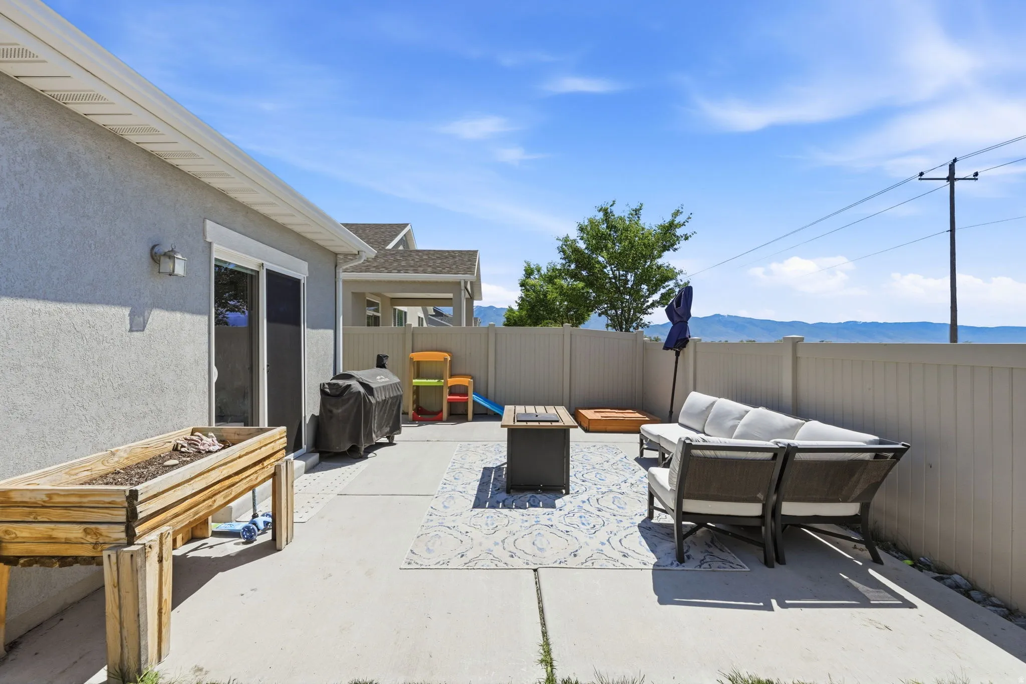 Expansive concrete patio with a privacy fence, sliding glass door access, and a mountain backdrop