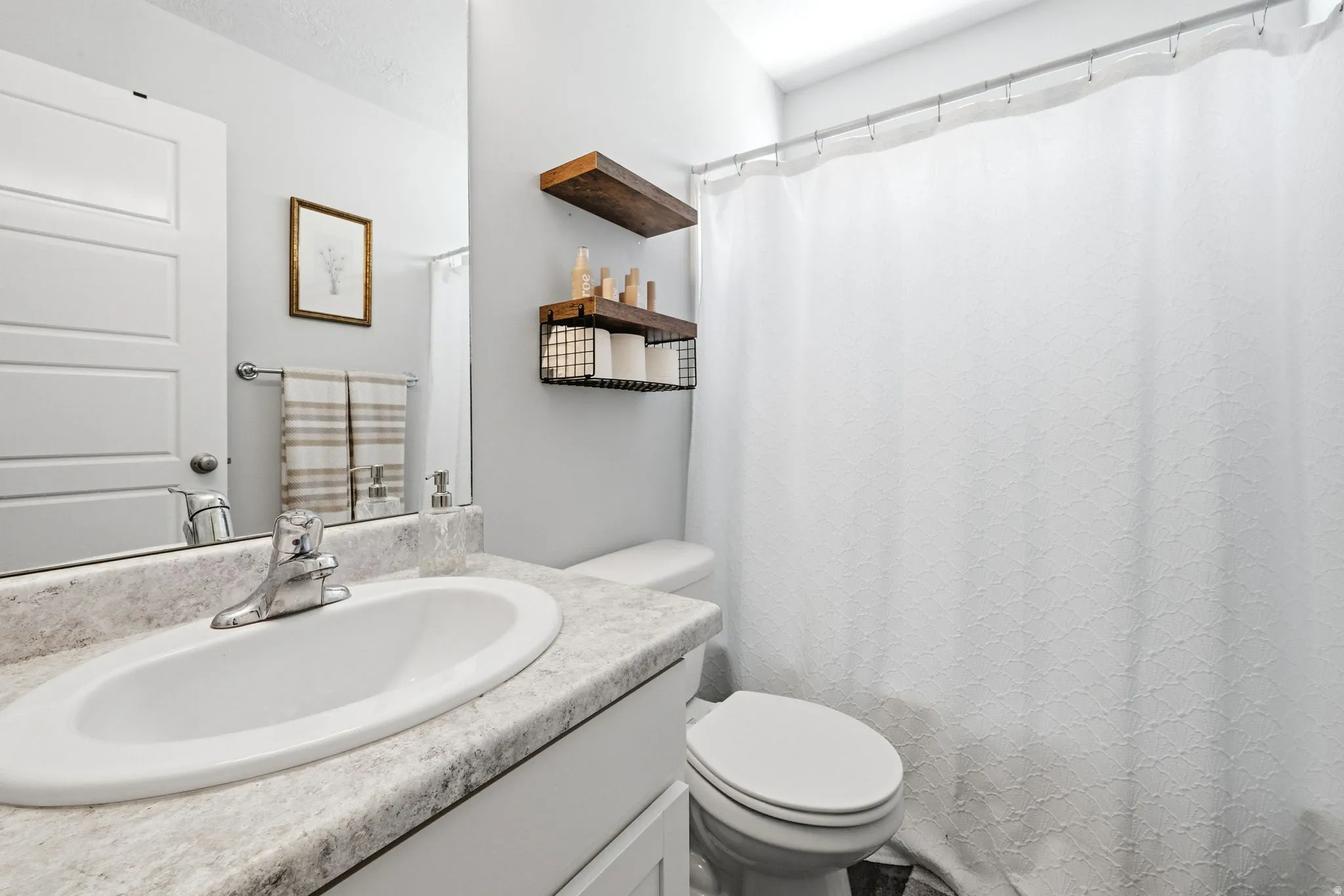 Bathroom vanity with an integrated oval sink, chrome faucet, and a light-toned countertop