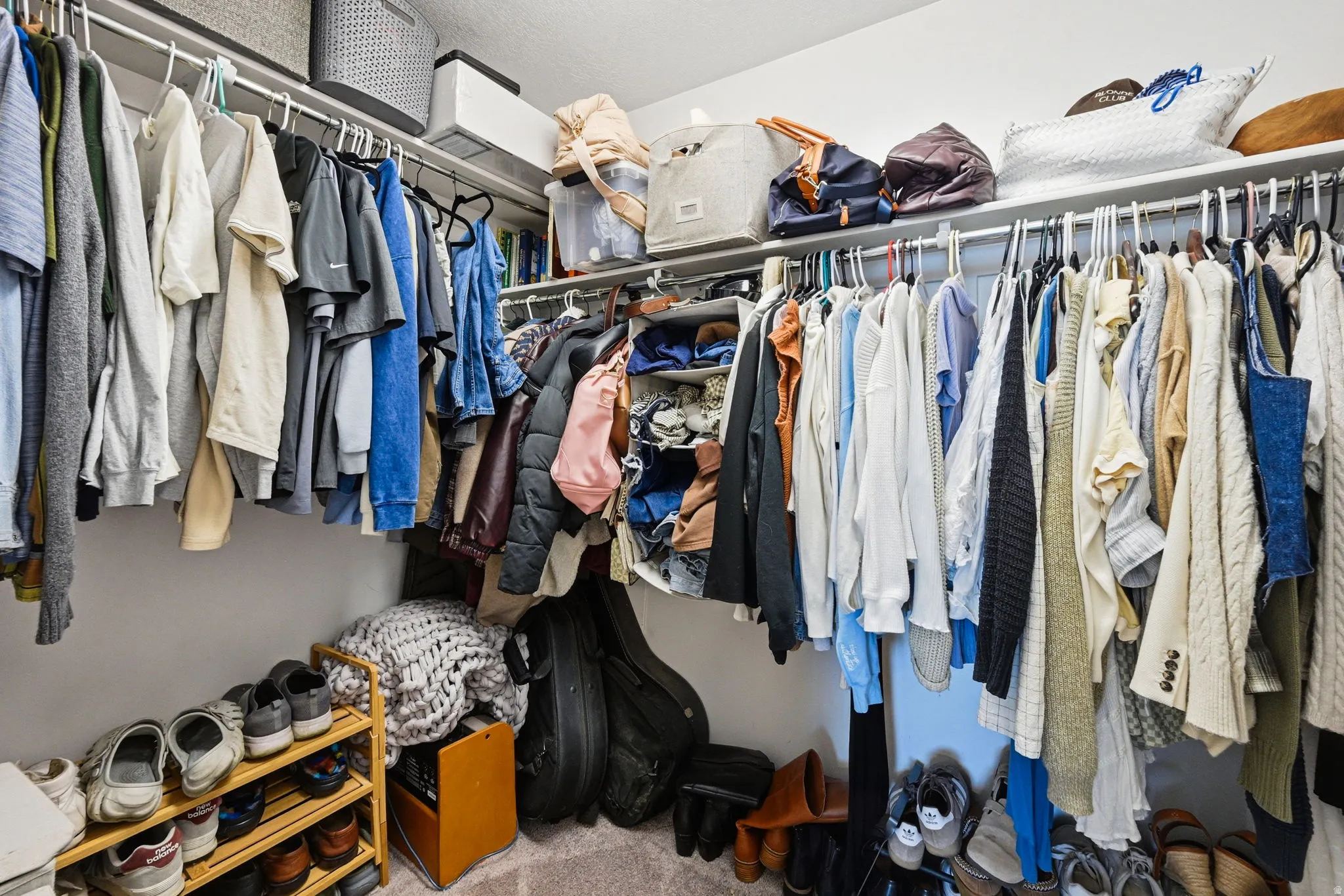 Custom closet system with multiple hanging rods, integrated shelving, and carpet flooring