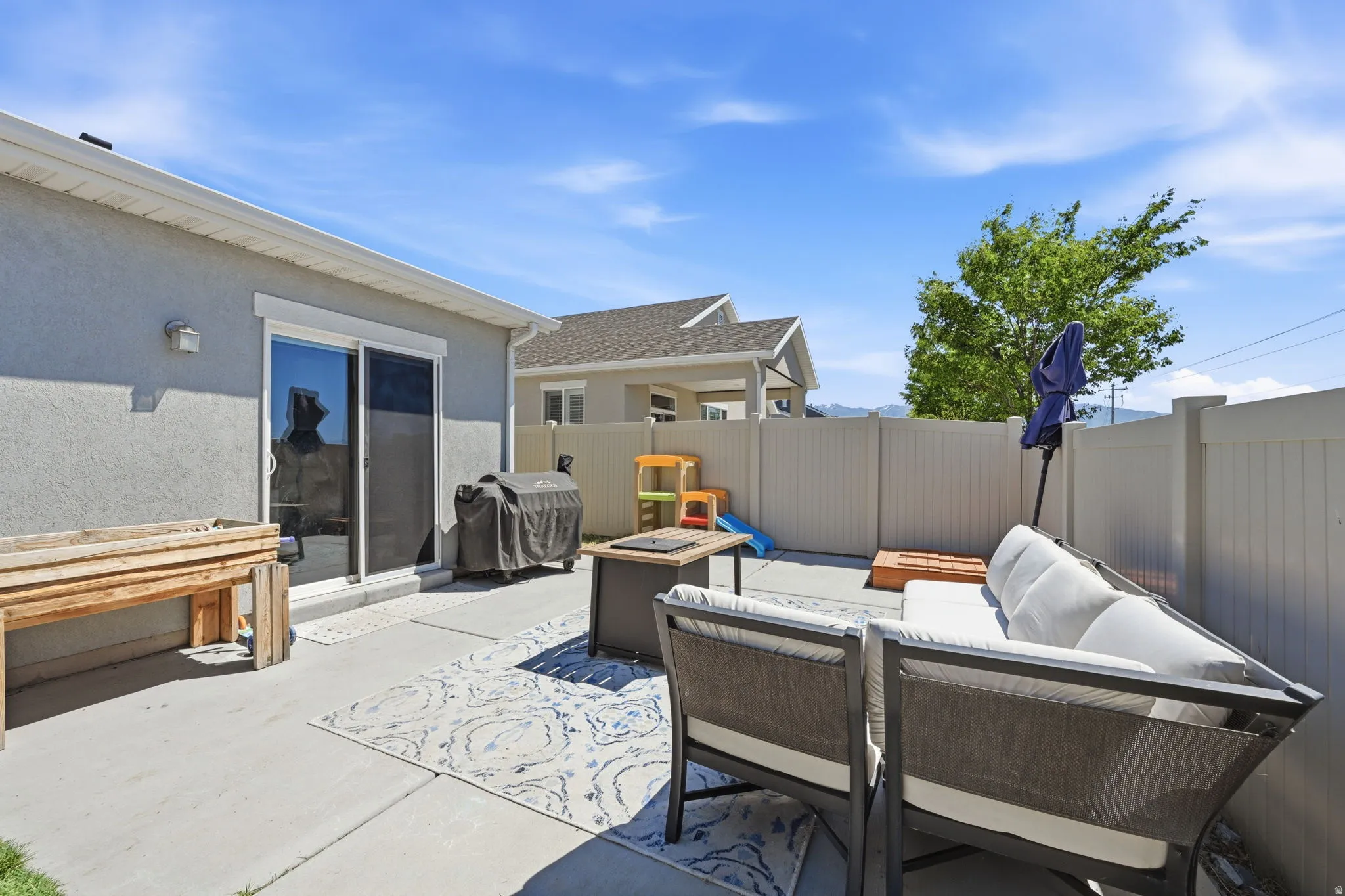 Private concrete patio featuring a sliding glass door entry, stucco exterior, and full vinyl fencing