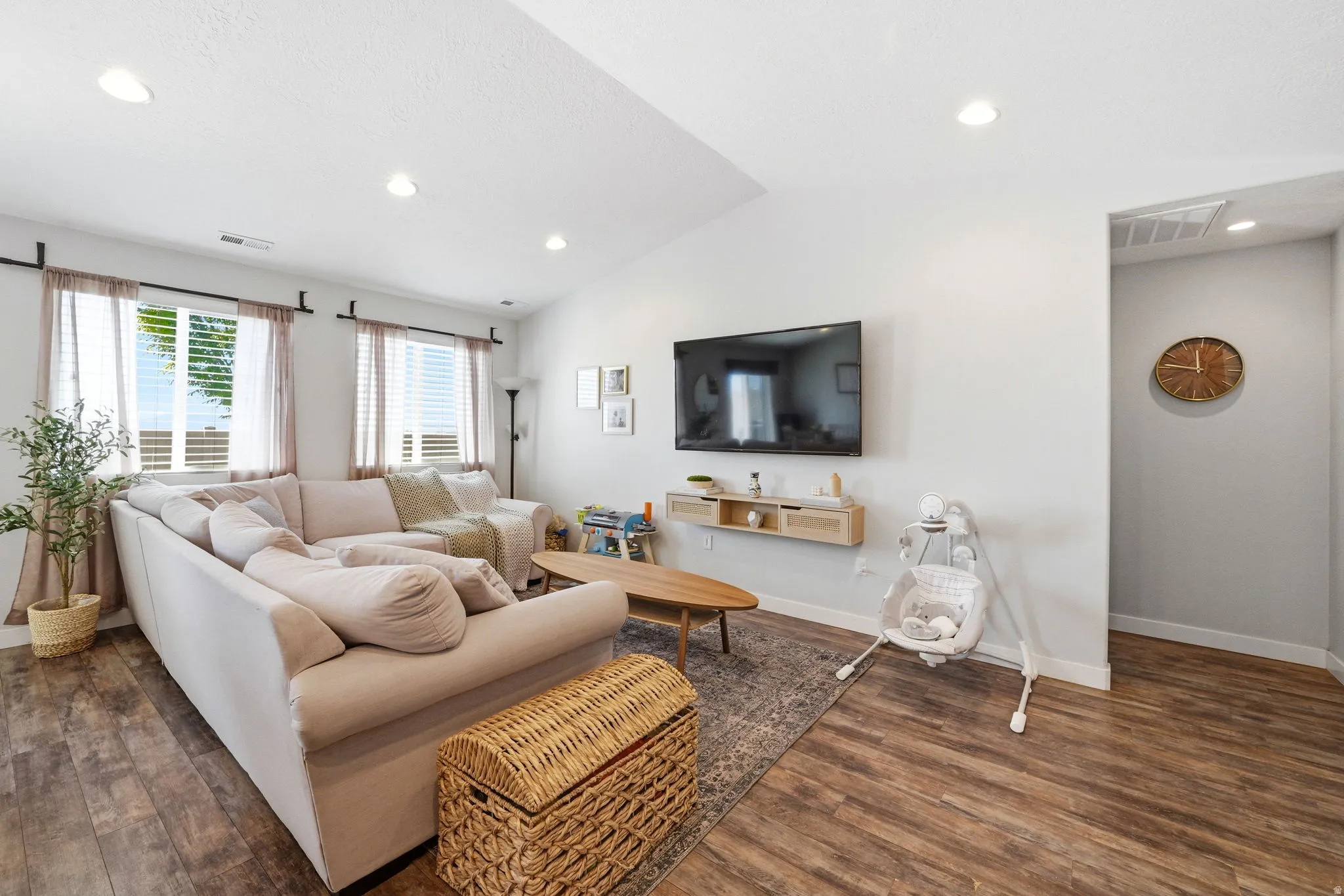 Spacious living area featuring wood-finish flooring, recessed lighting, and multiple windows with blinds