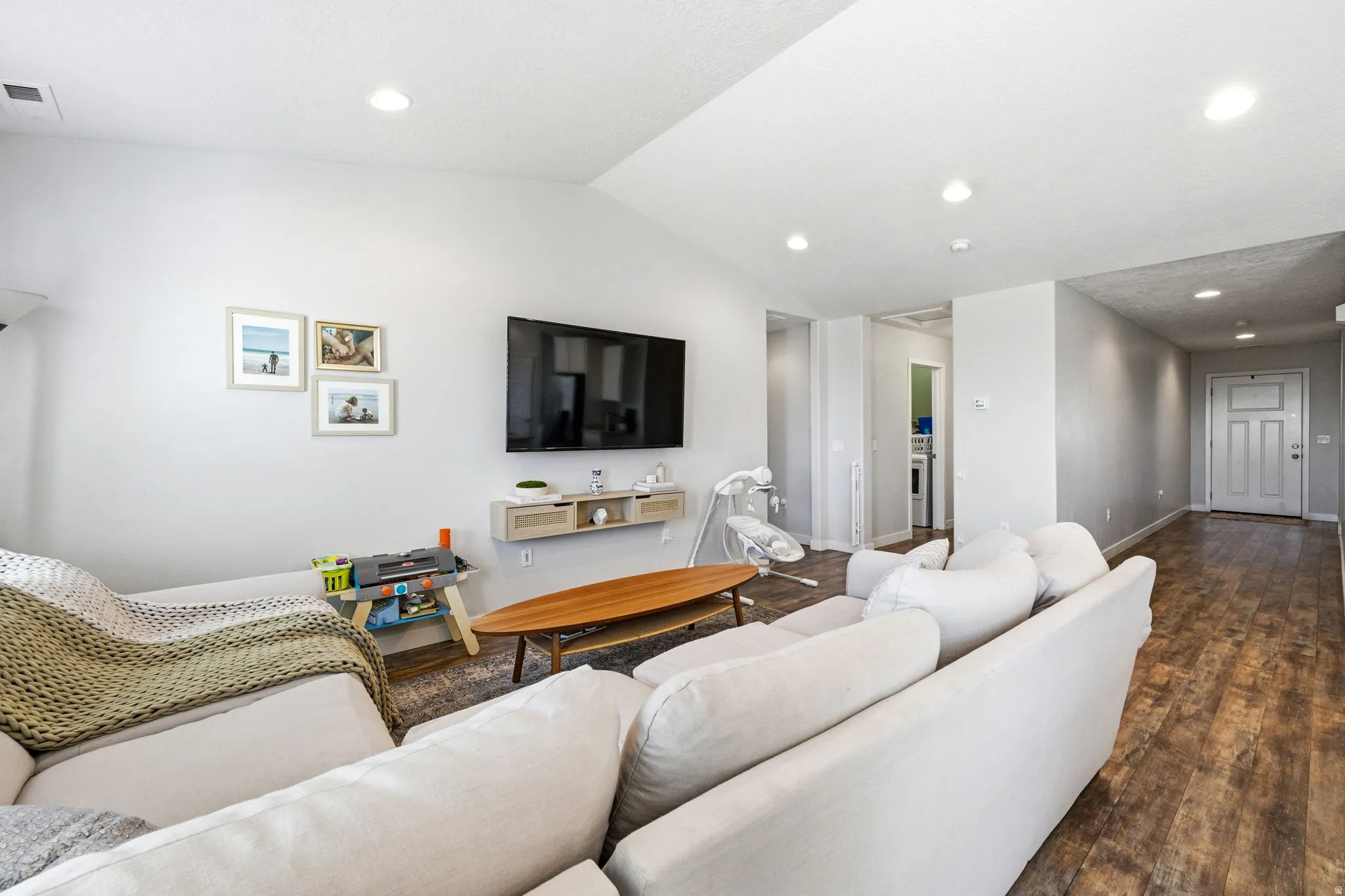 Spacious living area featuring light-toned walls, recessed lighting, and wood-finish flooring
