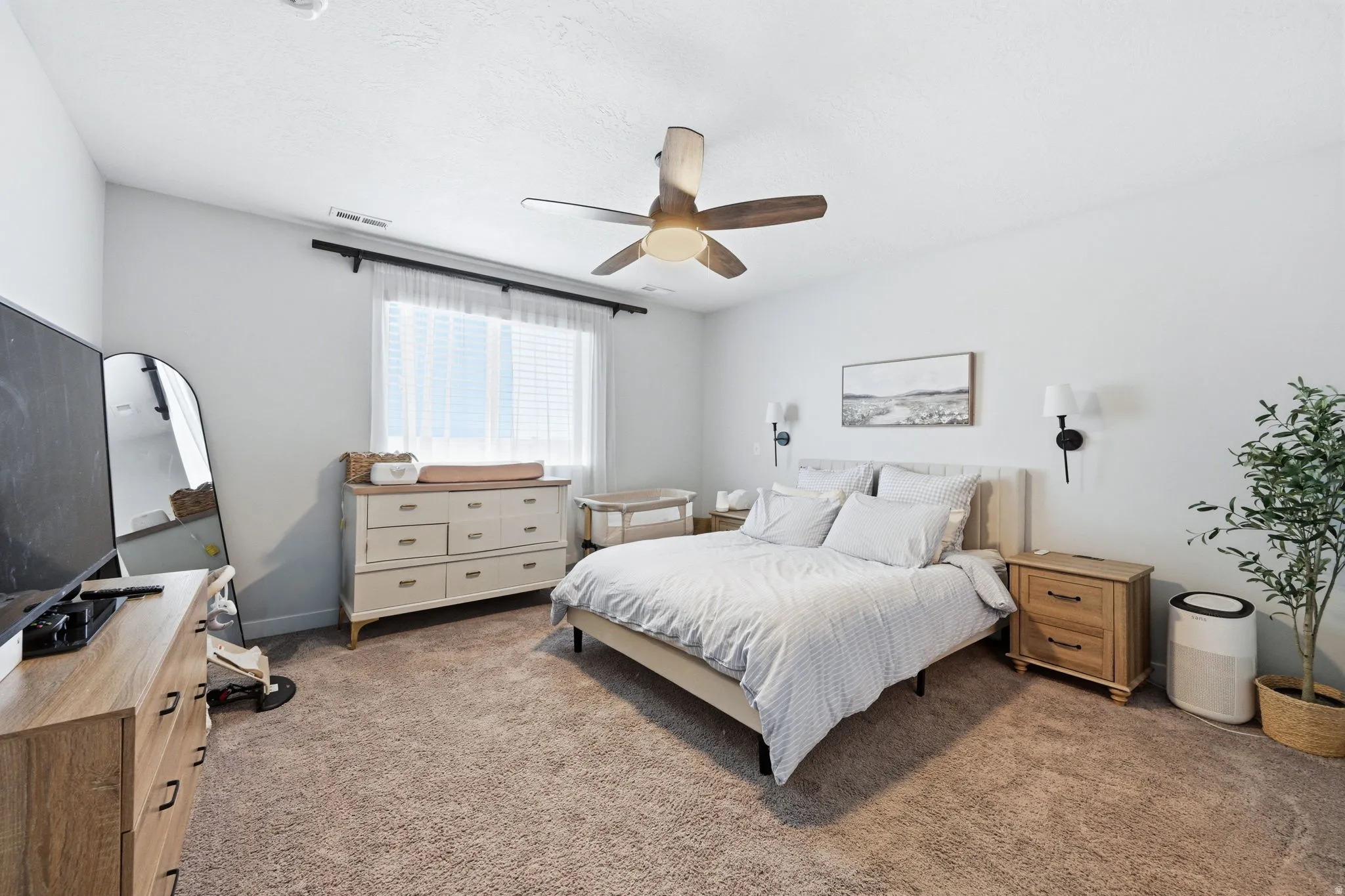Carpeted room featuring a ceiling fan with integrated lighting, a window with blinds and sheer curtains, and light-toned walls