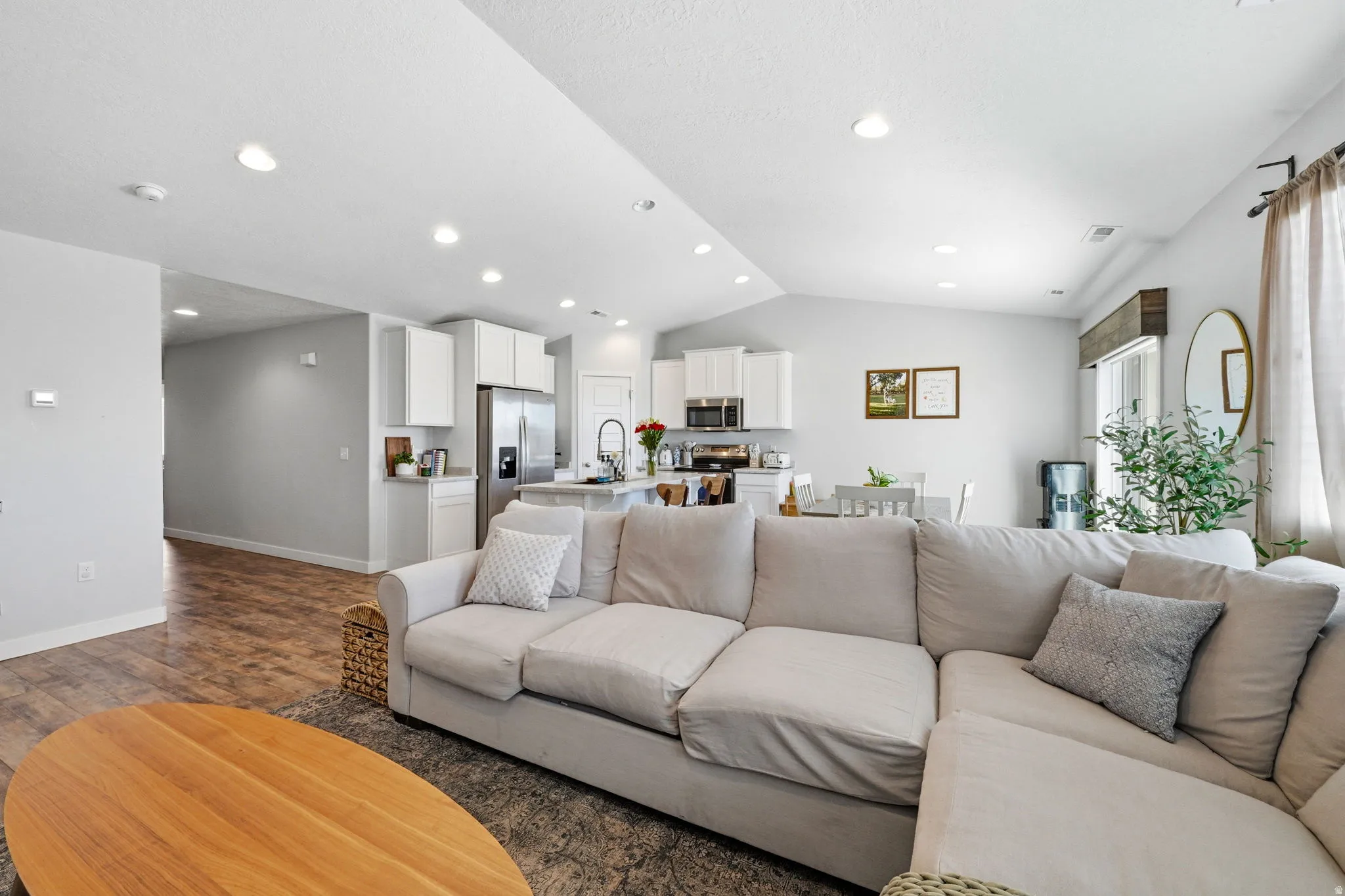 Open-concept living space featuring wood-finish flooring, recessed lighting, white cabinetry, and stainless steel appliances