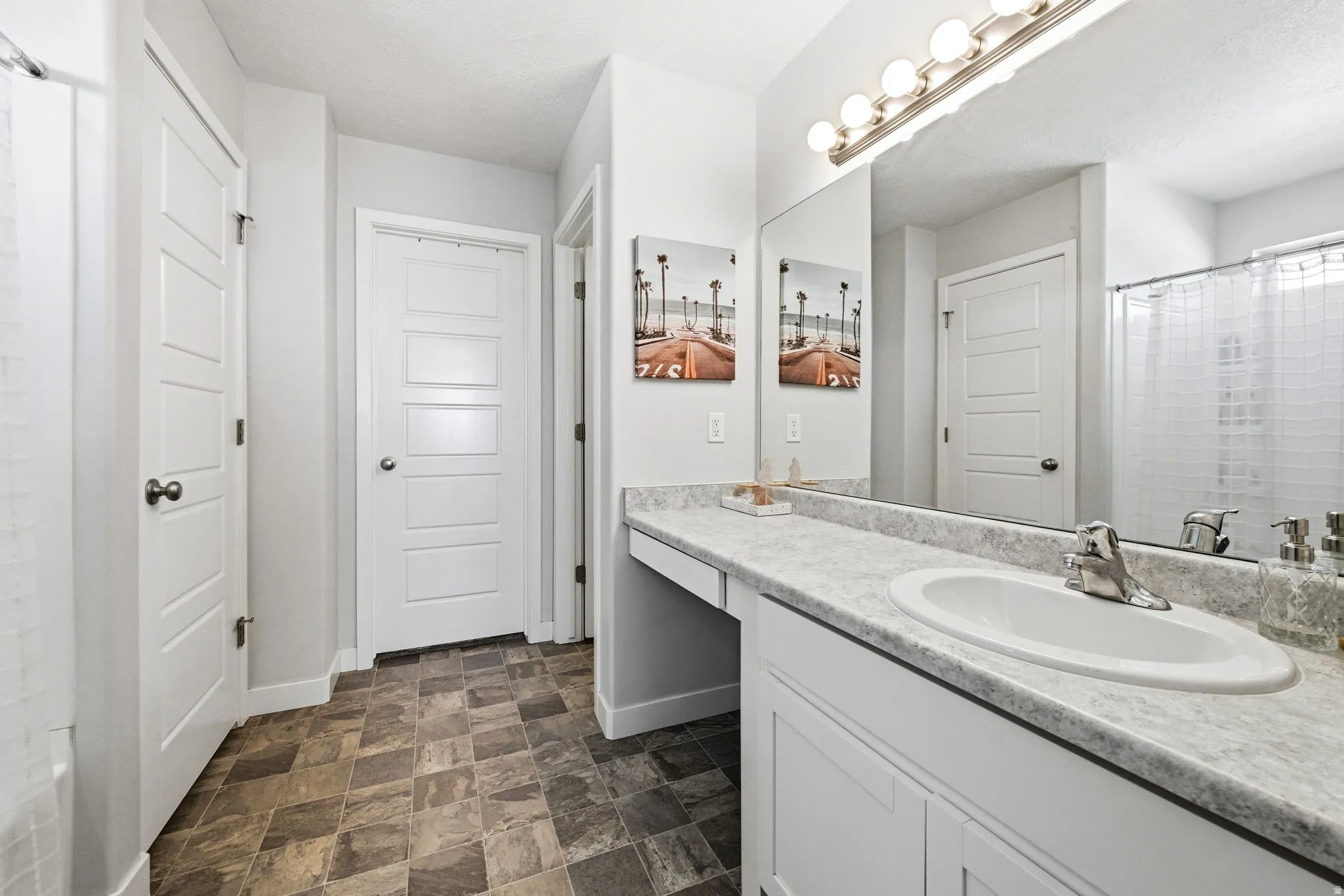 Bathroom featuring a single vanity with a white basin sink and chrome faucet, set against a light gray countertop