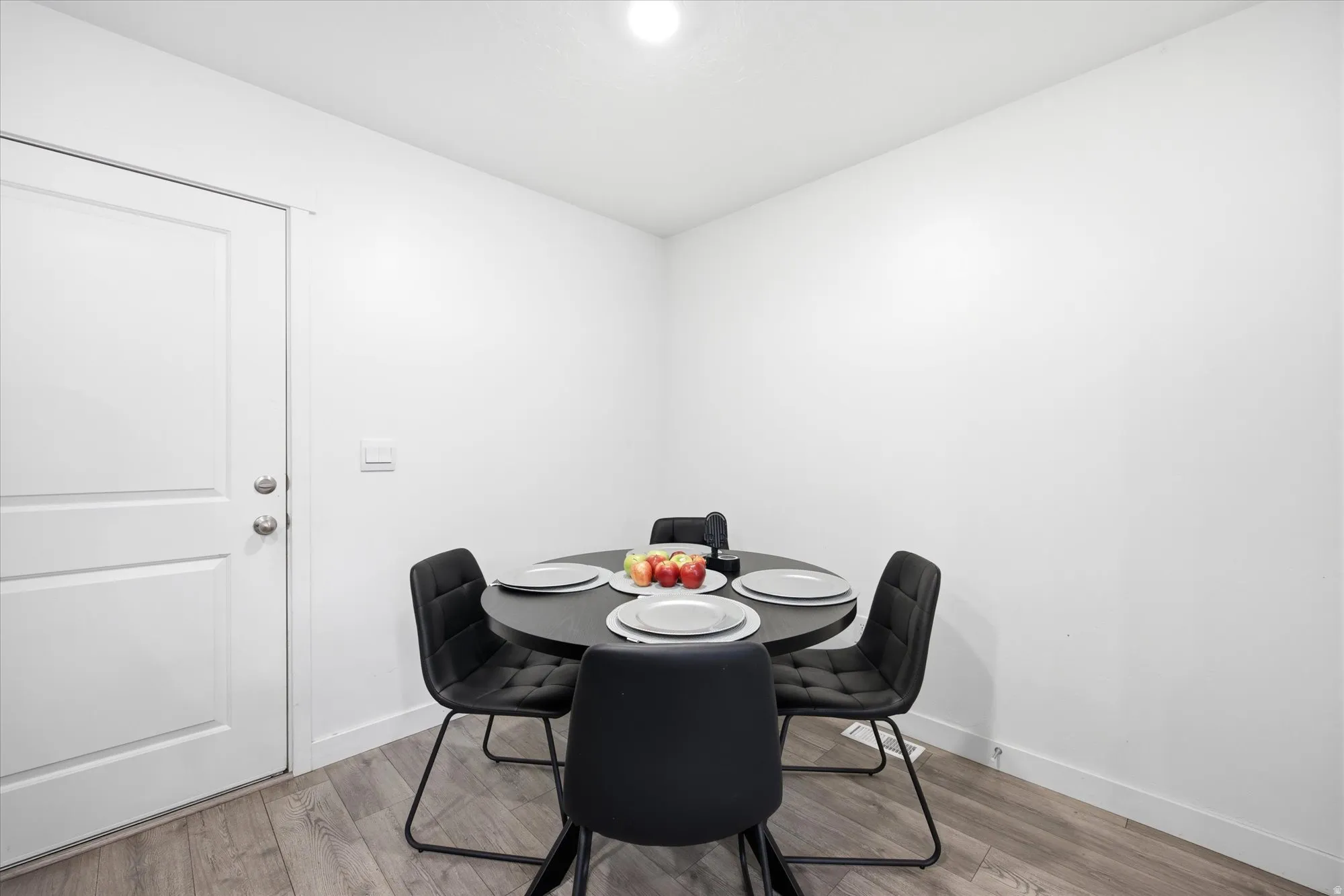 Bright dining area featuring wood-finish flooring, white walls, and a recessed ceiling light