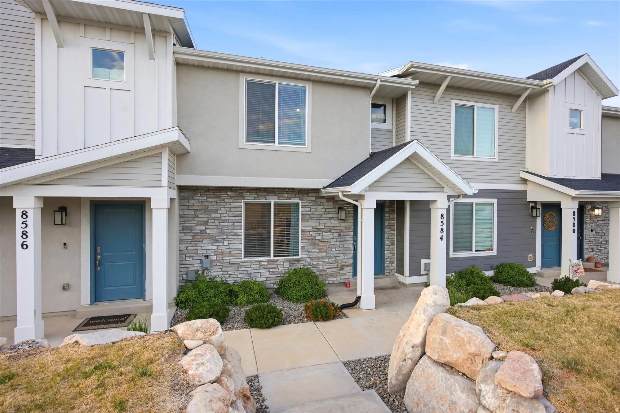 Contemporary multi-level townhome featuring a mix of horizontal siding, board-and-batten accents, and stone veneer detailing