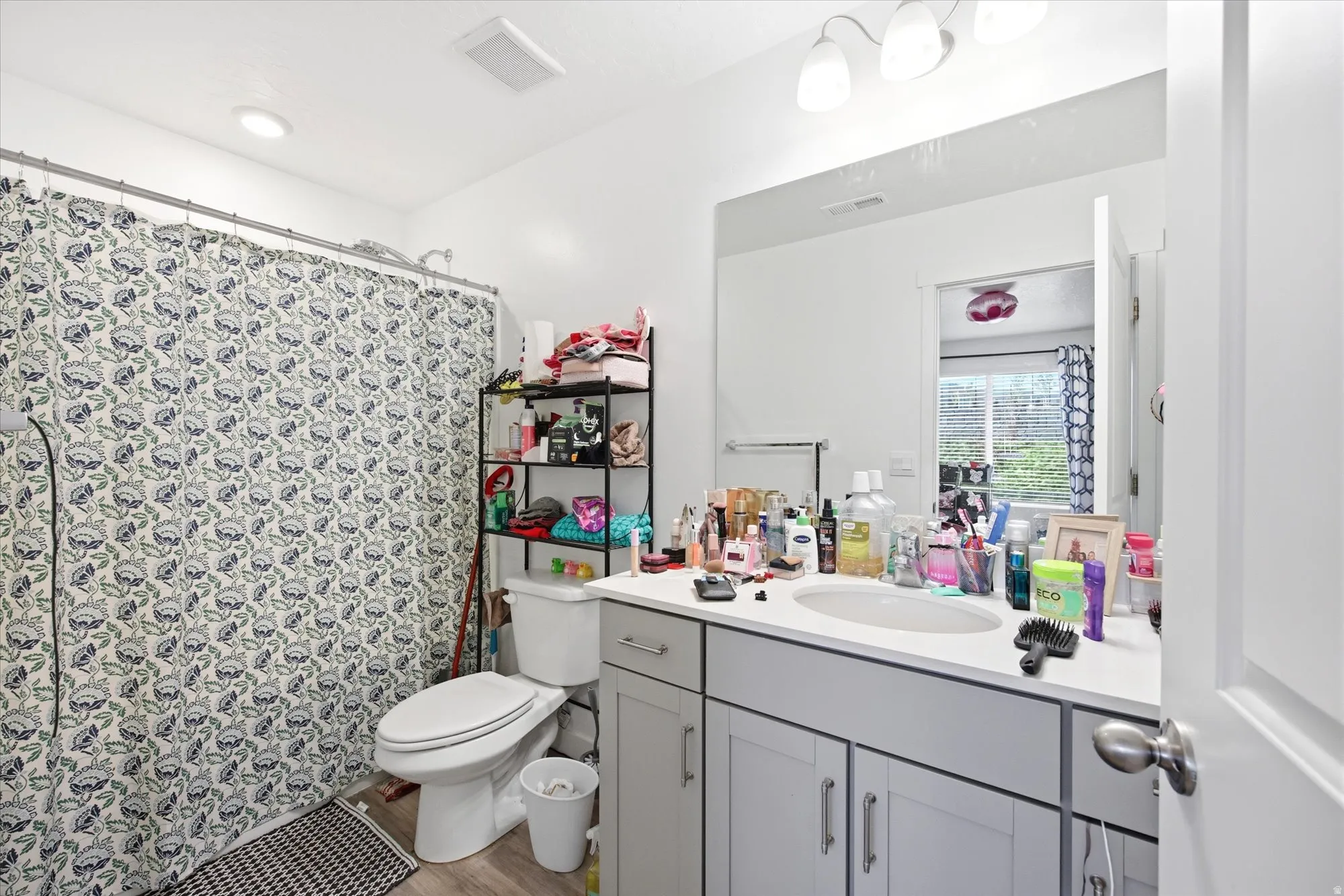 Bathroom featuring a dual-sink vanity with gray cabinetry, a wall-mounted mirror, and overhead lighting