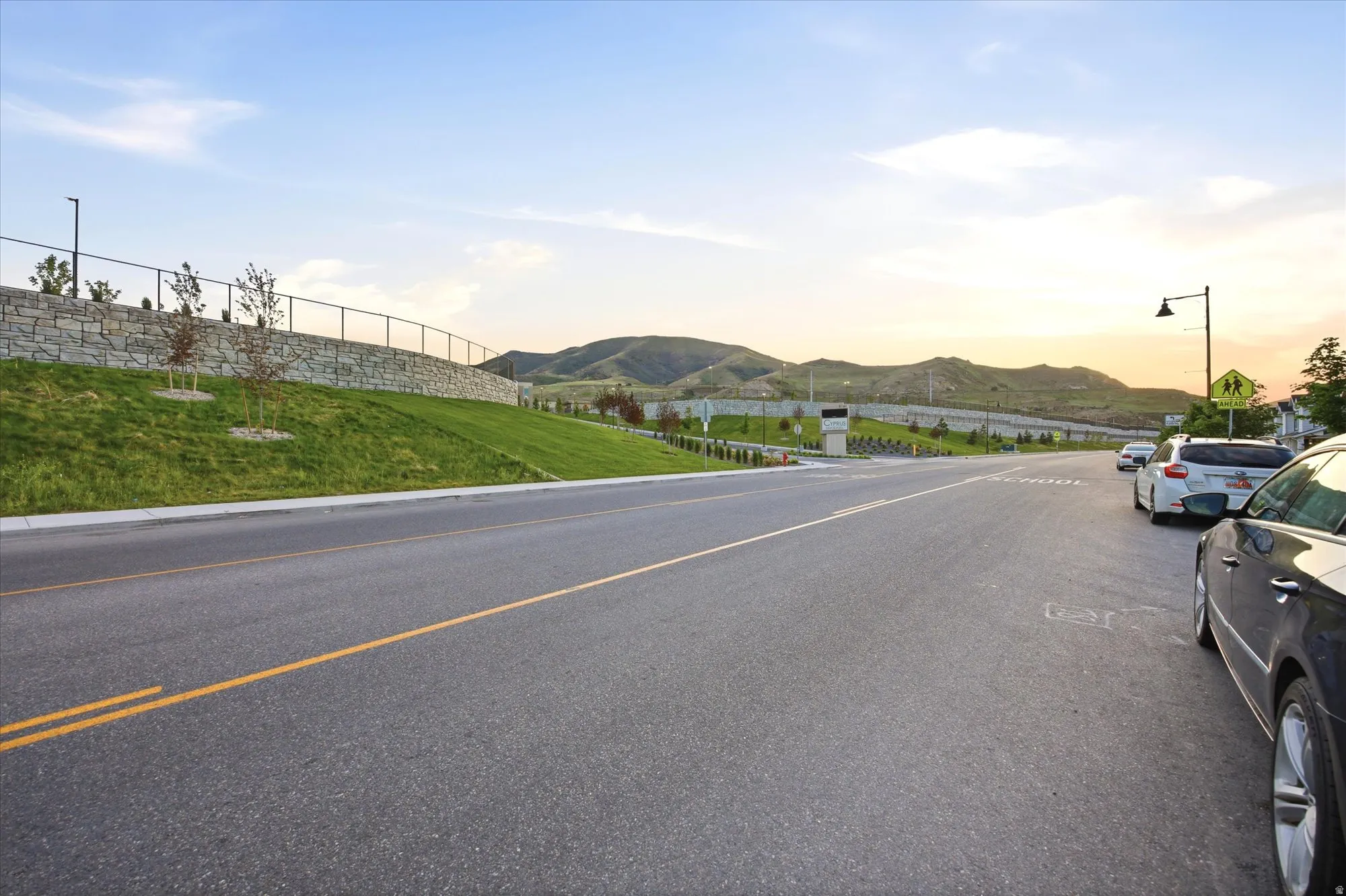 Paved street with striped lanes bordered by a manicured grassy slope