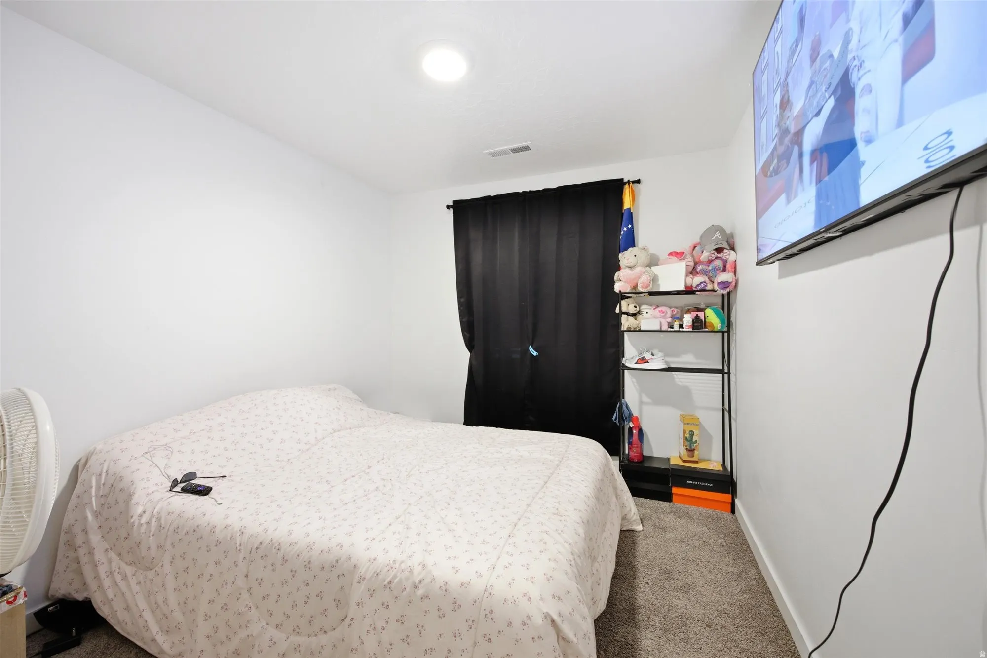 Carpeted room featuring a ceiling-mounted light fixture and a wall-mounted television