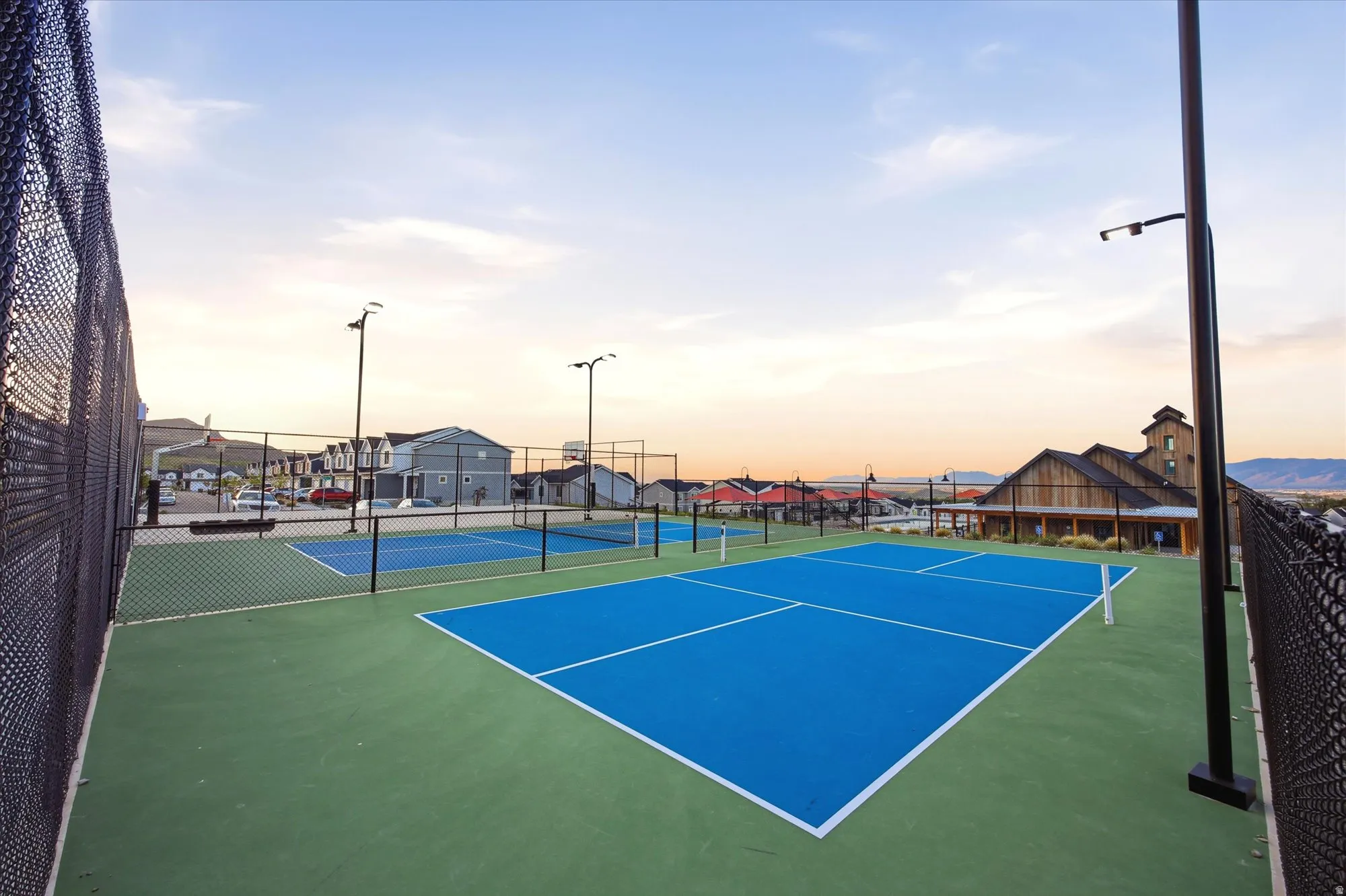 Multiple outdoor courts featuring blue playing surfaces and green surrounds